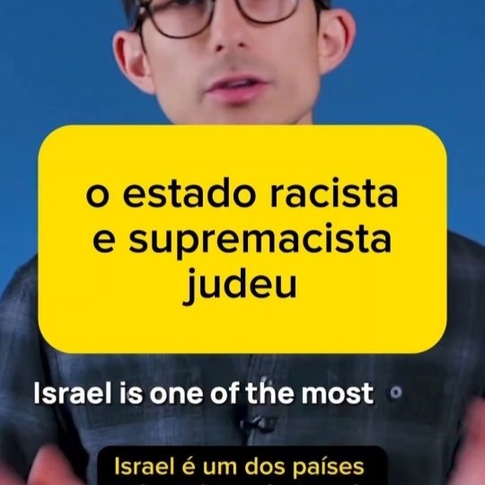 'o estado racista e supremacista judeu' em preto sobre fundo amarelo em cima de frame de vídeo mostrando um homem de pele bege clara, óculos e cabelo pretos e camisa xadrez cinza-azulada, e abaixo, a legenda 'Israel is one of the most' e a tradução 'Israel é um dos países'